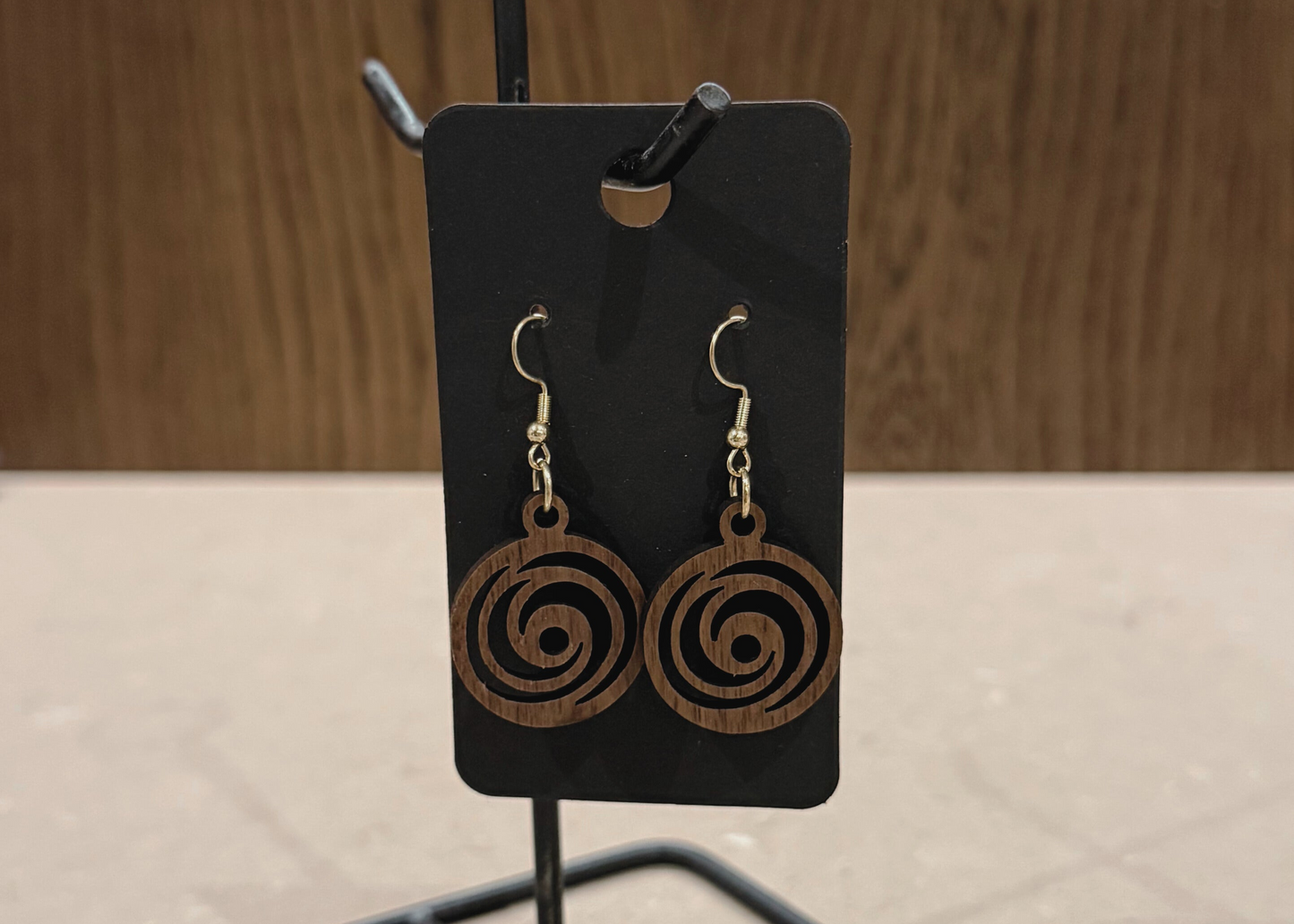 Wooden spiral earrings on a black card with a wooden background